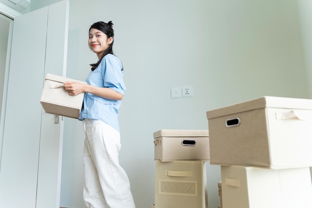 Junge asiatische Frau zieht in ein neues Haus um