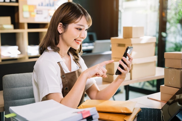 Junge asiatische Frauen, die ein Smartphone benutzen, kontaktierten einen Kunden und fragten nach einer Lieferadresse