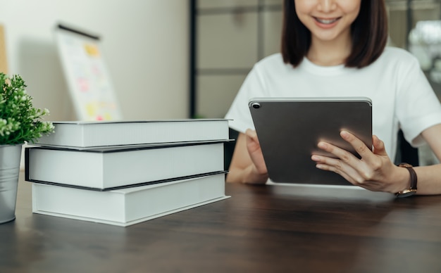 Junge asiatische Frauenhand, die digitales Tablett auf dem Haus hält.