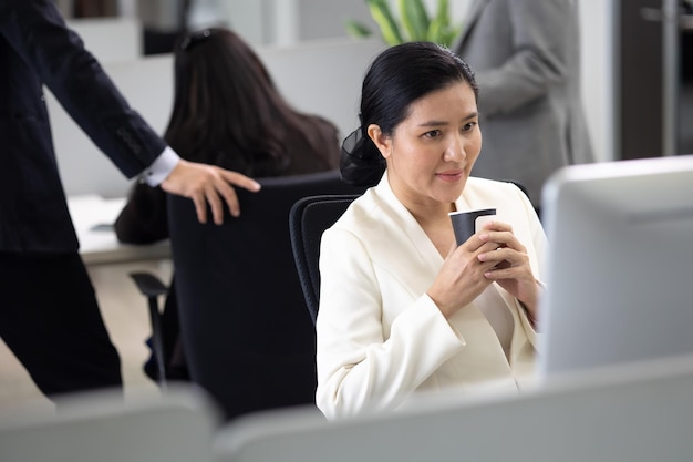 Junge asiatische Geschäftsfrau, die am Schreibtisch mit Desktop-Computer im modernen Heimbüro arbeitet