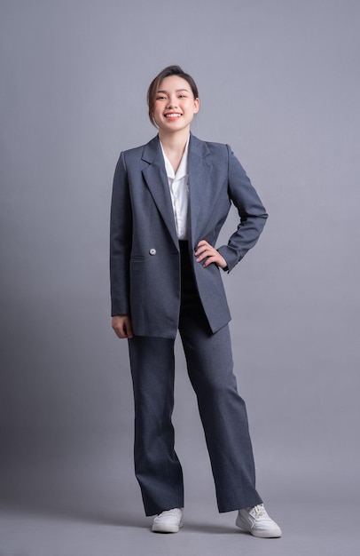 Junge asiatische Geschäftsfrau, die auf grauem Hintergrund steht