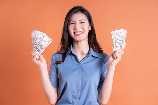 Junge asiatische Geschäftsfrau, die auf orange Hintergrund aufwirft
