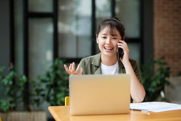 Junge asiatische Geschäftsfrau, die im Büro mit Mobiltelefon arbeitet