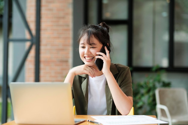 Junge asiatische Geschäftsfrau, die im Büro mit Mobiltelefon arbeitet