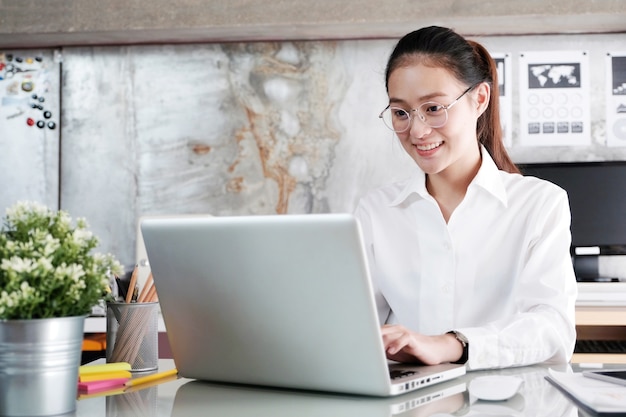 Junge asiatische Geschäftsfrau, die mit Laptop-Computer im Büro arbeitet