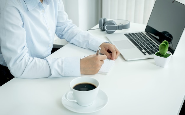 Junge asiatische Geschäftsfrau Hand zur Kenntnis nehmen und online von ihrem Heimbüro aus arbeiten, sozial distanzierendes Lehrkonzept während COVID-Viruskrankheiten.