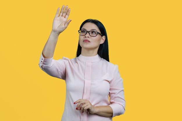 Junge asiatische Geschäftsfrau mit Brille berührt unsichtbaren Bildschirm mit ihrer Hand
