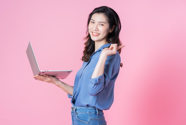 Junge asiatische Geschäftsfrau mit Laptop auf rosa Hintergrund