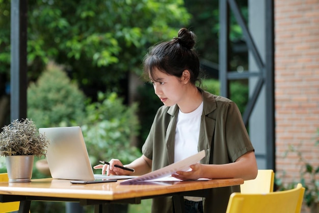 Junge asiatische Geschäftsfrau oder Studentin, die online am Computer-Laptop arbeitet