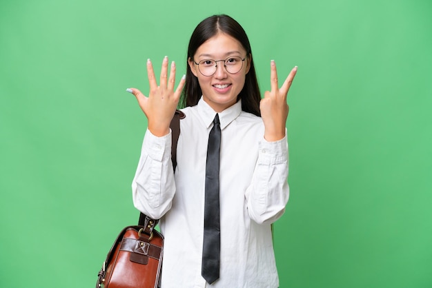 Junge asiatische Geschäftsfrau über isoliertem Hintergrund, die sieben mit den Fingern zählt