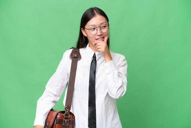 Junge asiatische Geschäftsfrau über lokalisiertem Hintergrund, der zur Seite schaut