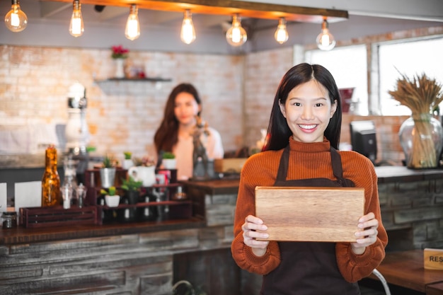 Junge asiatische Geschäftsinhaberin vor Café und Bäckerei