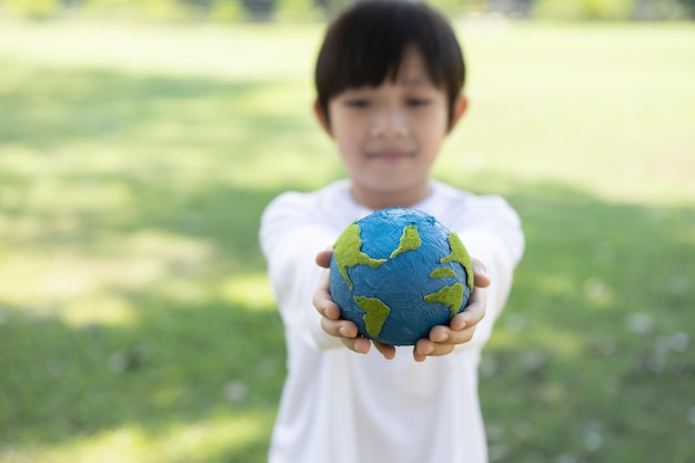 Junge asiatische Junge hält den Globus der Erde im Hintergrund des Naturparks Gyre