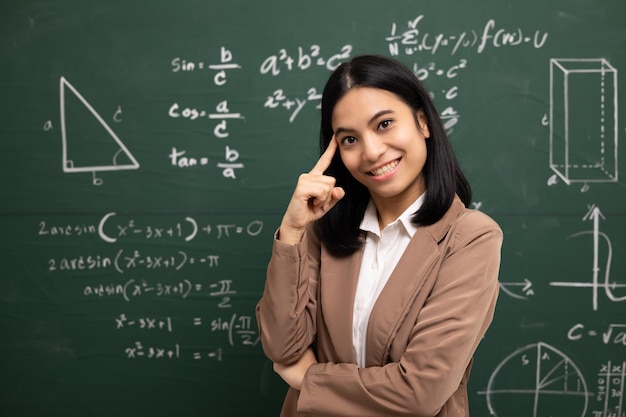 Junge asiatische Lehrerin steht mit Blick auf Kamera und Videokonferenz mit Studentin Lehrerin trainiert die Mathematik in der Klassenzimmertafel aus dem Online-Kurs