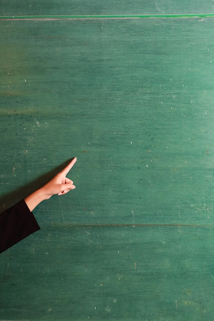 Foto junge asiatische lehrerinhand, die etwas auf altem grünem brett zeigt