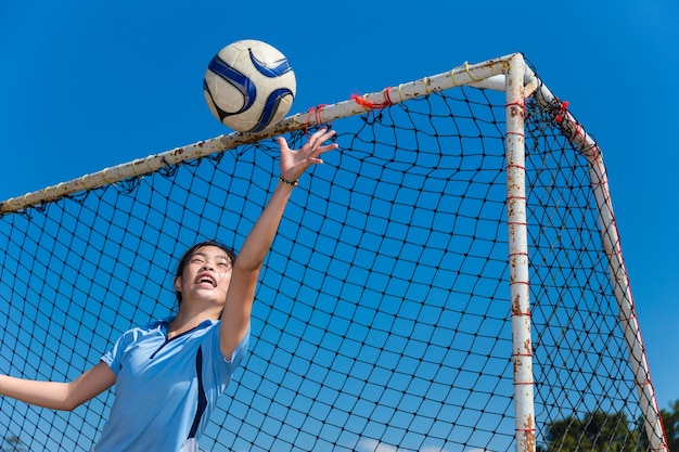 junge asiatische Mädchen Torhüter den Ball fangen