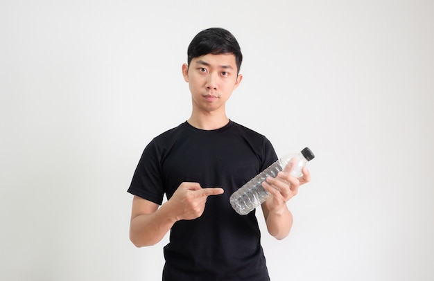 Junge asiatische Mann schwarzes Hemd zeigen Finger auf Plastikflasche in der Hand mit ernstem Gesicht Blick in die Kamera