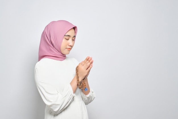 Junge asiatische muslimische Frau betet zu Gott mit Tasbih isoliert auf weißem Hintergrund