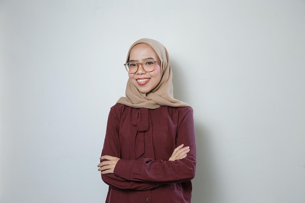 Junge asiatische muslimische Frau mit Brille sieht selbstbewusst und glücklich isoliert auf weißem Hintergrund aus