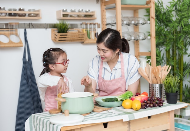 Junge asiatische Mutter bringt ihrer Tochter das Kochen bei