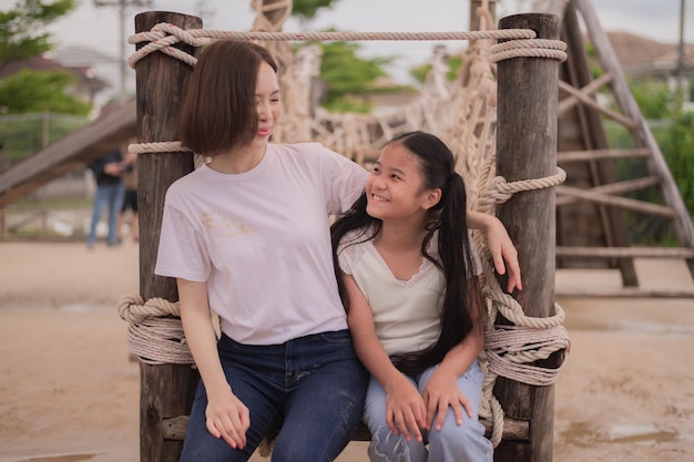 Junge asiatische Mutter und Tochter umarmen sich auf dem Spielplatz