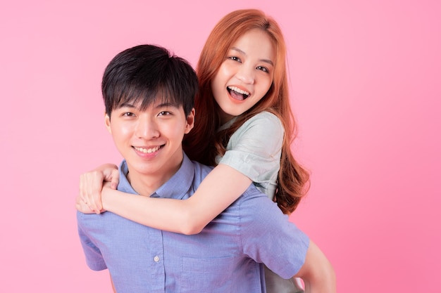 Junge asiatische Paare, die auf rosa Hintergrund aufwerfen