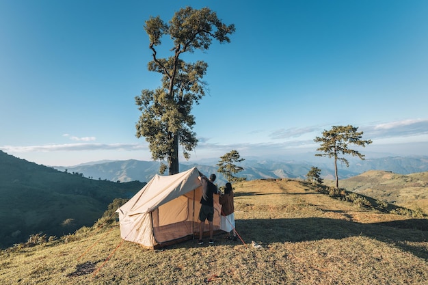 Junge asiatische Paare schlagen in den Sommerferien ein Zelt auf einem Campingplatz auf einem Berghügel im Nationalpark auf