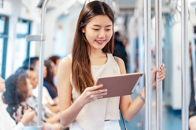 Junge asiatische Passagierin mit Multimedia-Player über Technologie-Tablet in der U-Bahn?