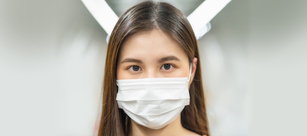 Junge asiatische Passagierin mit Mundschutz und Blick in die Kamera in der U-Bahn