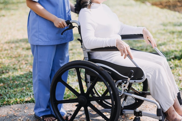 Junge asiatische Physiotherapeutin arbeitet mit einer älteren Frau am Gehen mit einem Geher.