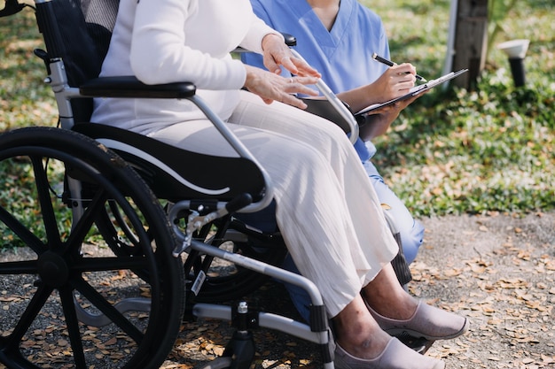 Junge asiatische Physiotherapeutin arbeitet mit einer älteren Frau am Gehen mit einem Geher.