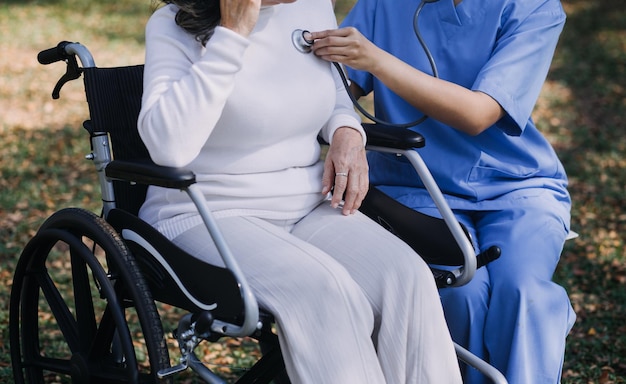 Junge asiatische Physiotherapeutin arbeitet mit einer älteren Frau am Gehen mit einem Geher.