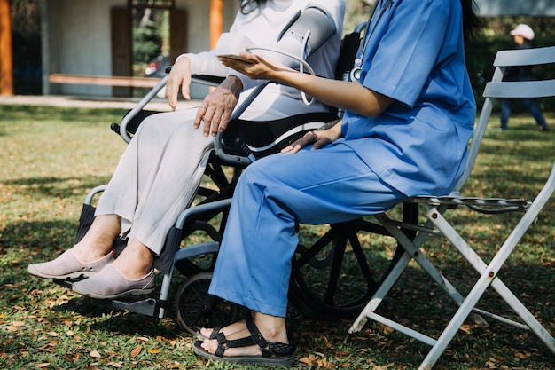 Junge asiatische Physiotherapeutin, die mit einer älteren Frau beim Gehen mit einer Gehhilfe arbeitet