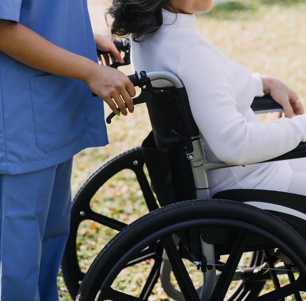 Junge asiatische Physiotherapeutin, die mit einer älteren Frau beim Gehen mit einer Gehhilfe arbeitet