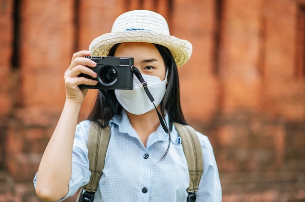 Junge asiatische rucksacktouristin mit hut und schutzmaske auf reisen in historischer stätte