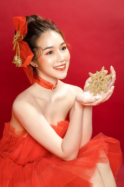 Junge asiatische schöne Frau Modell in einem noblen, stilvollen roten Luxuskleid auf rotem Hintergrund isoliert