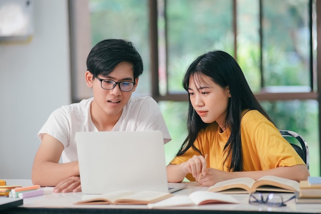 Junge asiatische Studenten, die zusammen mit Freunden lesen, lernen zusammen mit Freunden