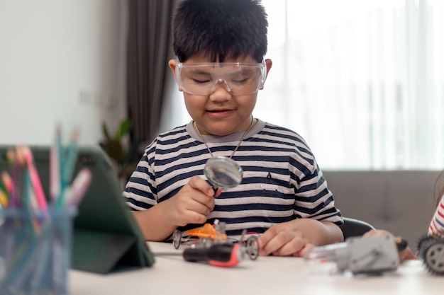 Junge asiatische Studenten lernen aus der Ferne online zu Hause in der Codierung von Roboterautos und elektronischen Platinenkabeln in MINT-DAMPF-Mathematikingenieur-Wissenschaftstechnologie-Computercode in Robotik für Kinder