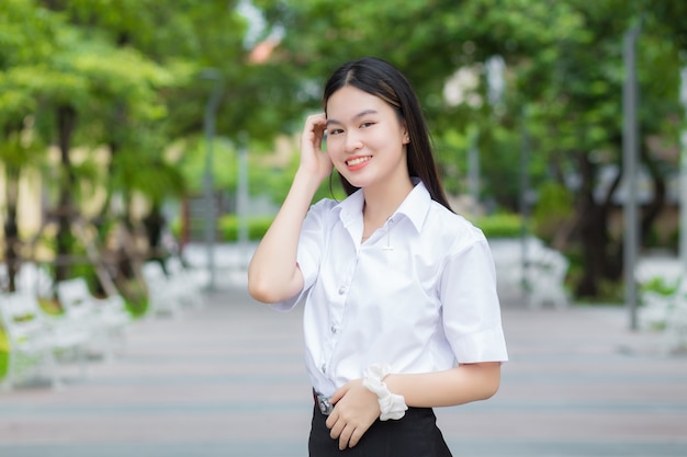 Junge asiatische Studentin, die blonde lange Haare hat, lächelt und schaut in die Kamera