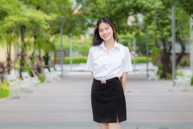 Junge asiatische Studentin, die blonde lange Haare hat, lächelt, während sie in der Universität steht