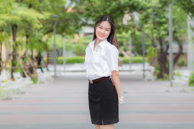 Junge asiatische Studentin, die blondes langes Haar hat, während sie in der Universität mit Outdoor steht