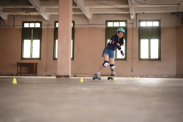 Junge asiatische Teenagerin, die Skateboard-Stadtsport spielt, fröhlicher und lustiger Lebensstil mit Skateboarding