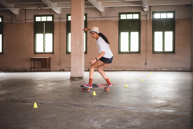 Junge asiatische Teenagerin, die Skateboard-Urban-Sport spielt, fröhlicher und lustiger Lebensstil mit Skateboarding