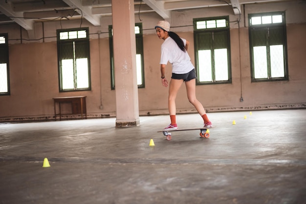 Junge asiatische Teenagerin, die Skateboard-Urban-Sport spielt, fröhlicher und lustiger Lebensstil mit Skateboarding