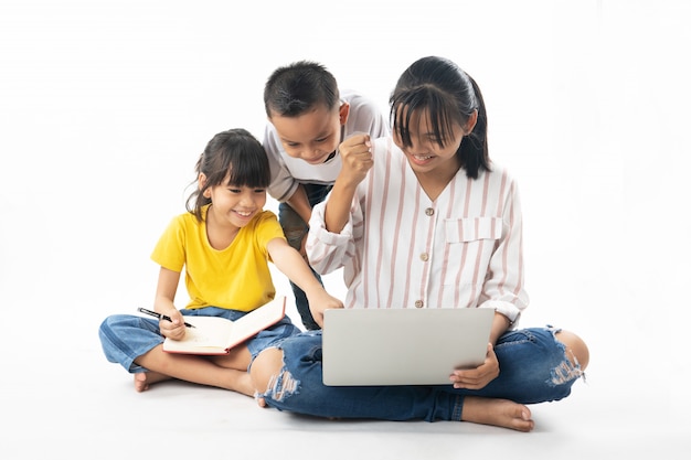 Junge asiatische thailändische Kinder, Junge und Mädchen, die auf Laptop durch Technologie und Multimedia lernen und schauen