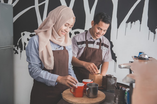 Junge asiatische weibliche und männliche Kellnerin im Café