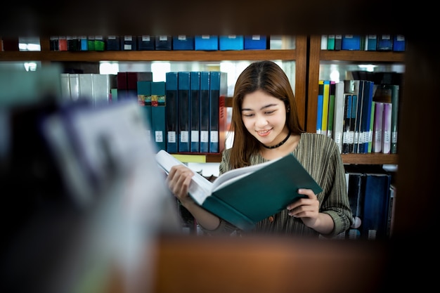 Junge Asien-Frau, die öffentlich eine Bibliothek des Grünbuchs hält.