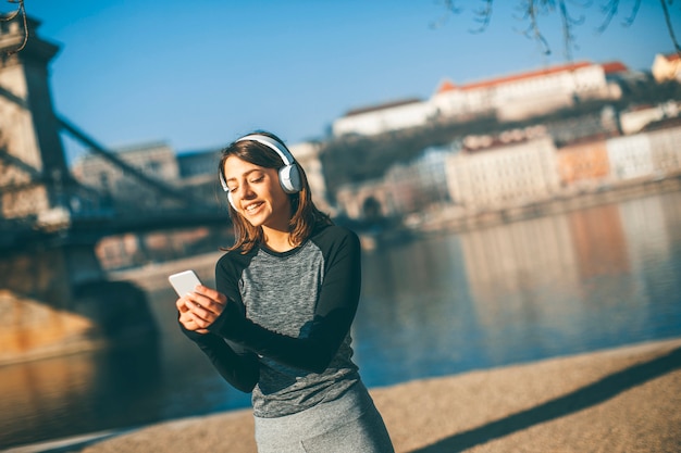 Junge Athletenfrau mit dem Handy im Freien