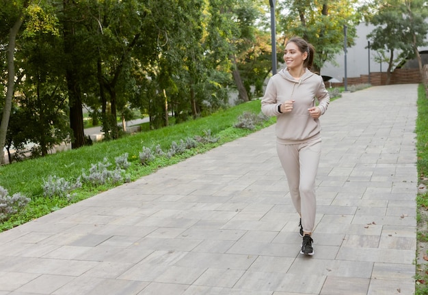 Junge athletische Frau in Sportkleidung, die morgens im Freien im Park joggt