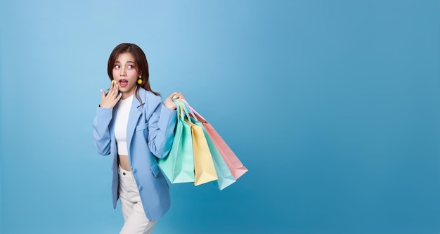 Junge, attraktive, asiatische Shopperin, Frau mit Einkaufstasche, die sich aufgeregt fühlt. Wow für die Rabatt-Promotion.